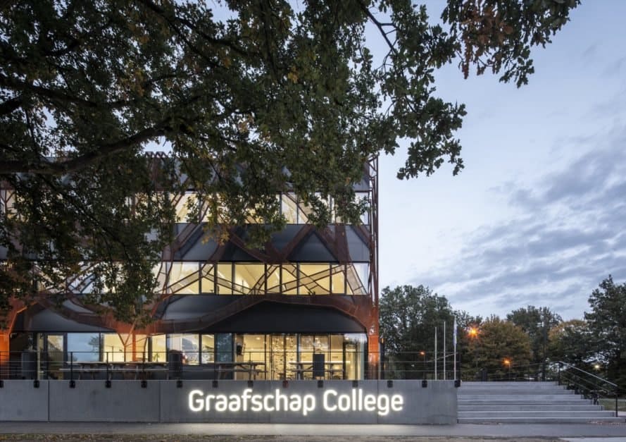 black building with giant weathered steel tree shapes over the facade and a sign that reads "Graafschap College"