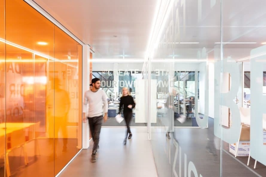 person walking next to a bright orange glass wall